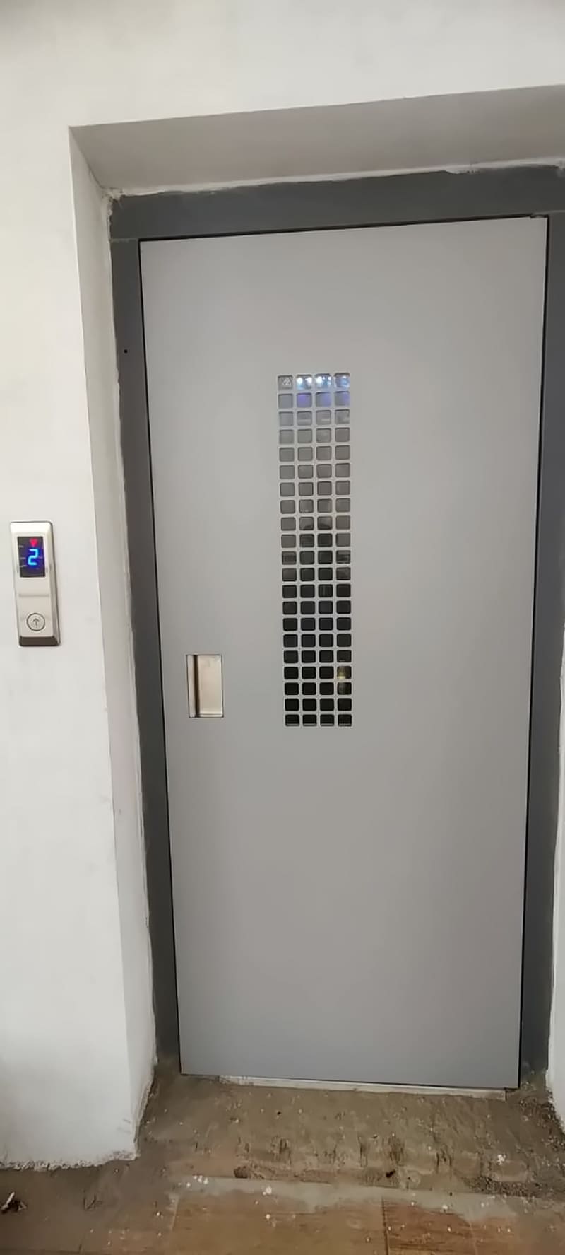 Grey swing-type lift landing door with a vertical vision strip